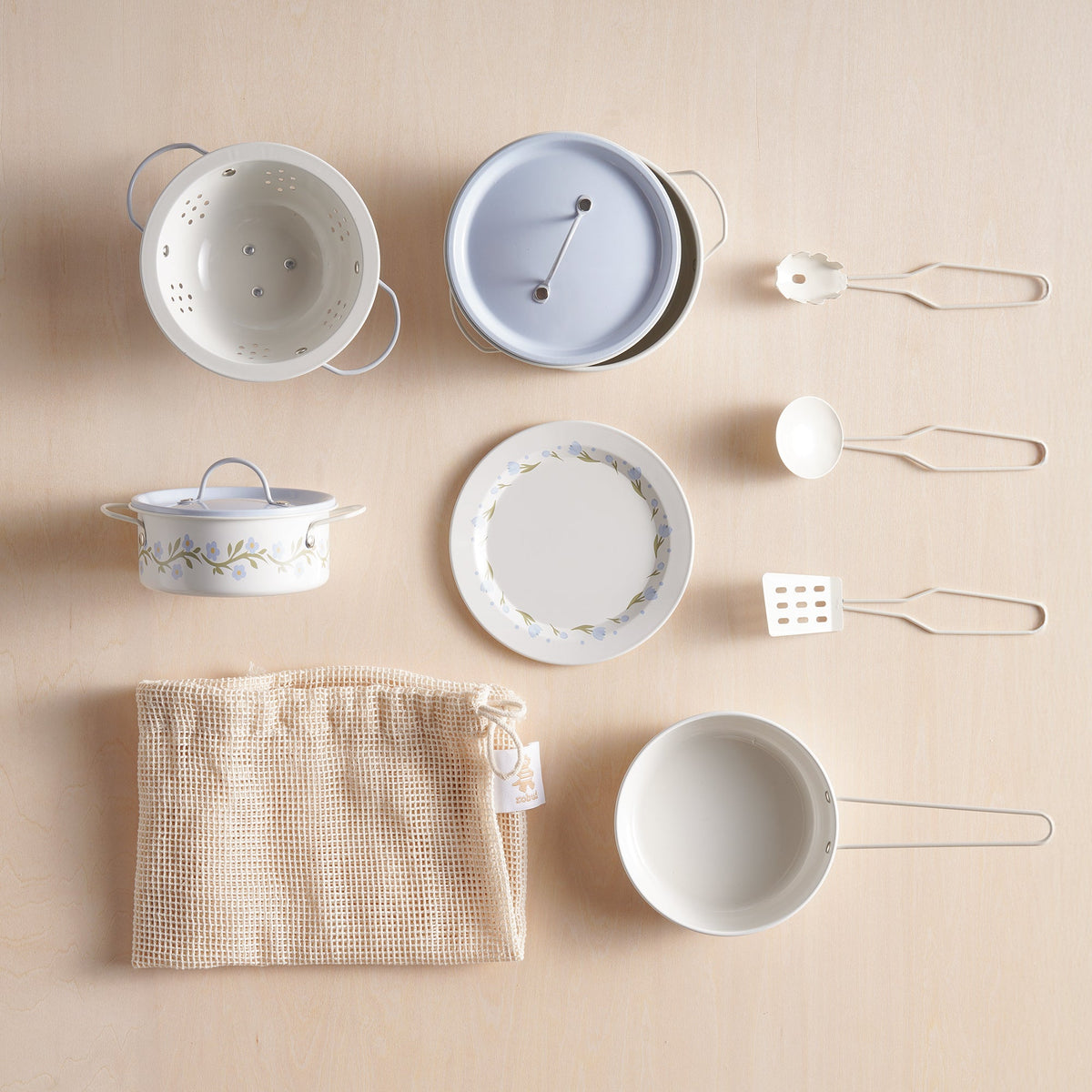 Flat lay of the complete ROBUD tinplate utensil set: colander, floral pot, plate, ladle, spatula, frying pan, and muslin bag.