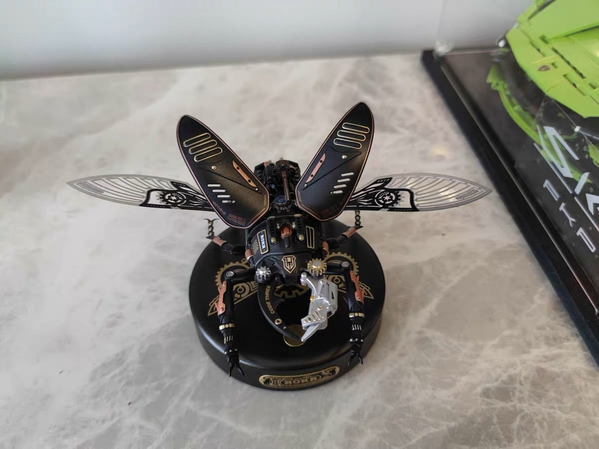 ROKR dark metal insect model on a circular display base with a product box and colorful items in the background