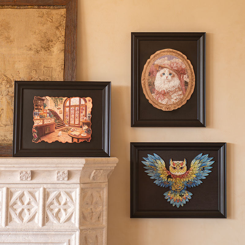 Rowood wooden puzzle collection showing three completed framed puzzles displayed on a cream wall, including a white cat portrait, an owl, and a fantasy shop interior