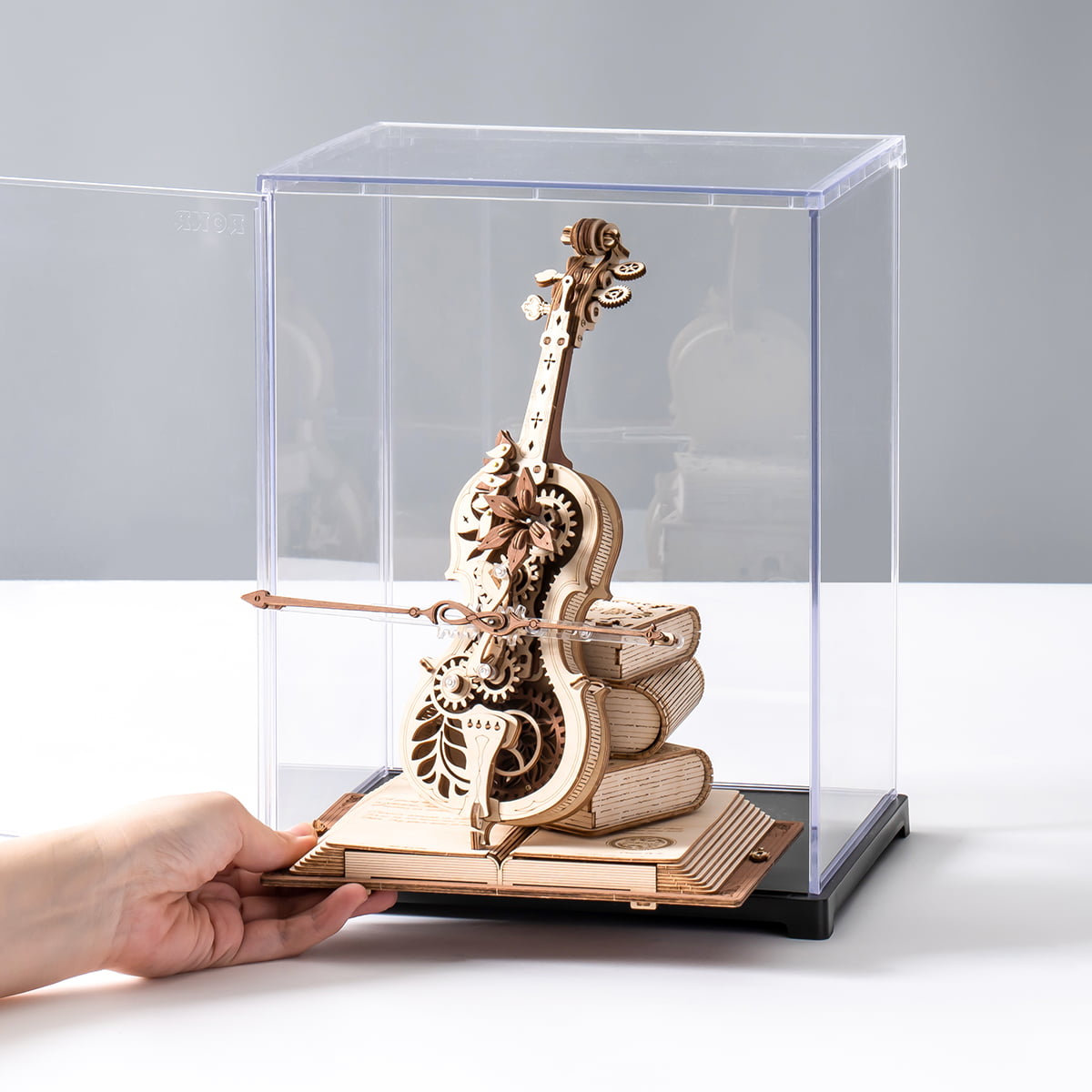 ROKR Magic Cello display case with a hand demonstrating the front door opening mechanism