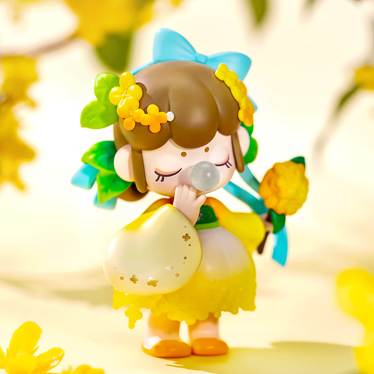 Close-up of a Rolife Nanci Flower Stories Campsis figure with brown hair, yellow floral crown, blue ribbon and yellow petal skirt holding a translucent orb against a blurred yellow flower background