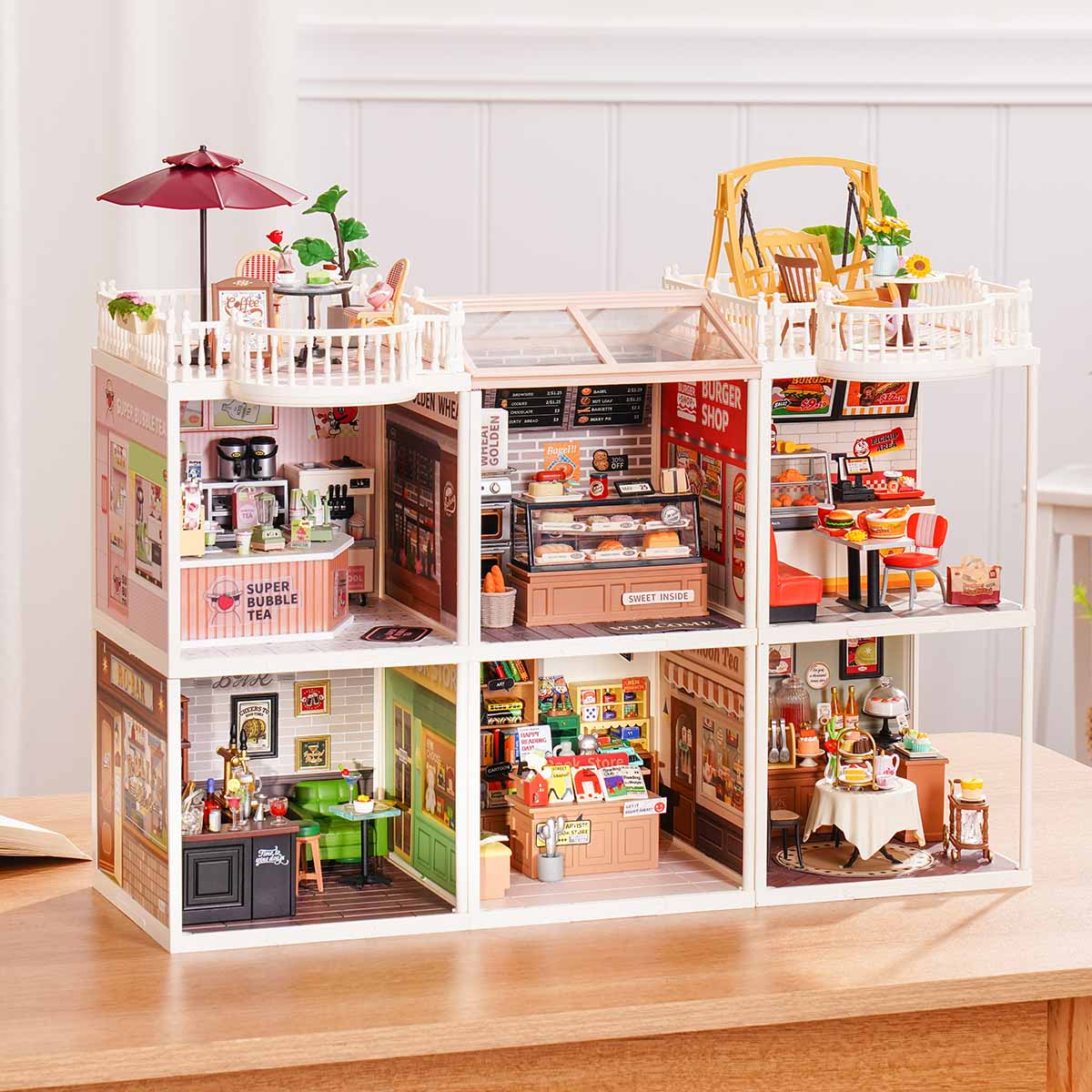 Rolife Super Creator Series 6-in-1 Six Grid miniature with a pink home theme showing six rooms including bedroom, clawfoot bathroom, pink bedroom, kitchen, dining room, and living room on a table.