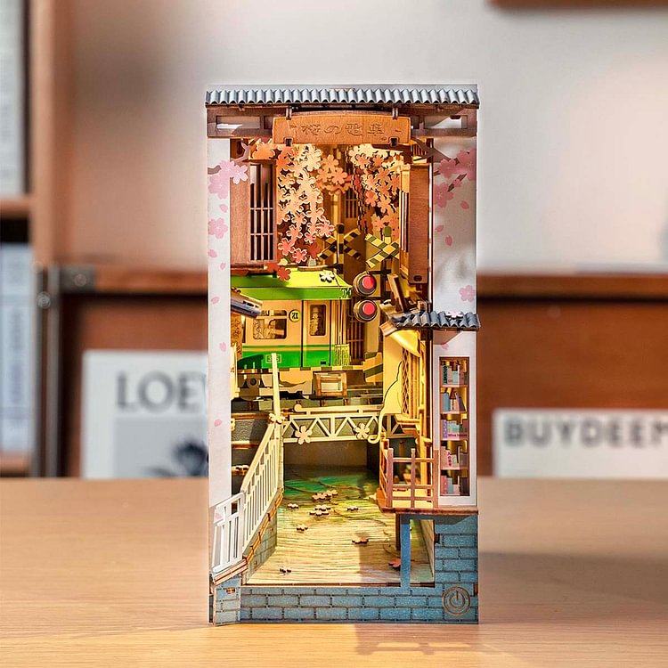 Rolife cherry blossom alley book nook with pink blooms, a canal bridge and miniature figures tucked between real books