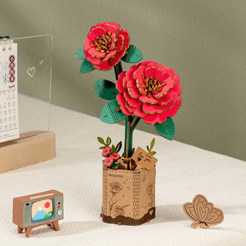 Ein Paar roter Rowood Holzblumen steht in einem Pflanzgefäß im Papiertüten-Stil auf einem Regal.