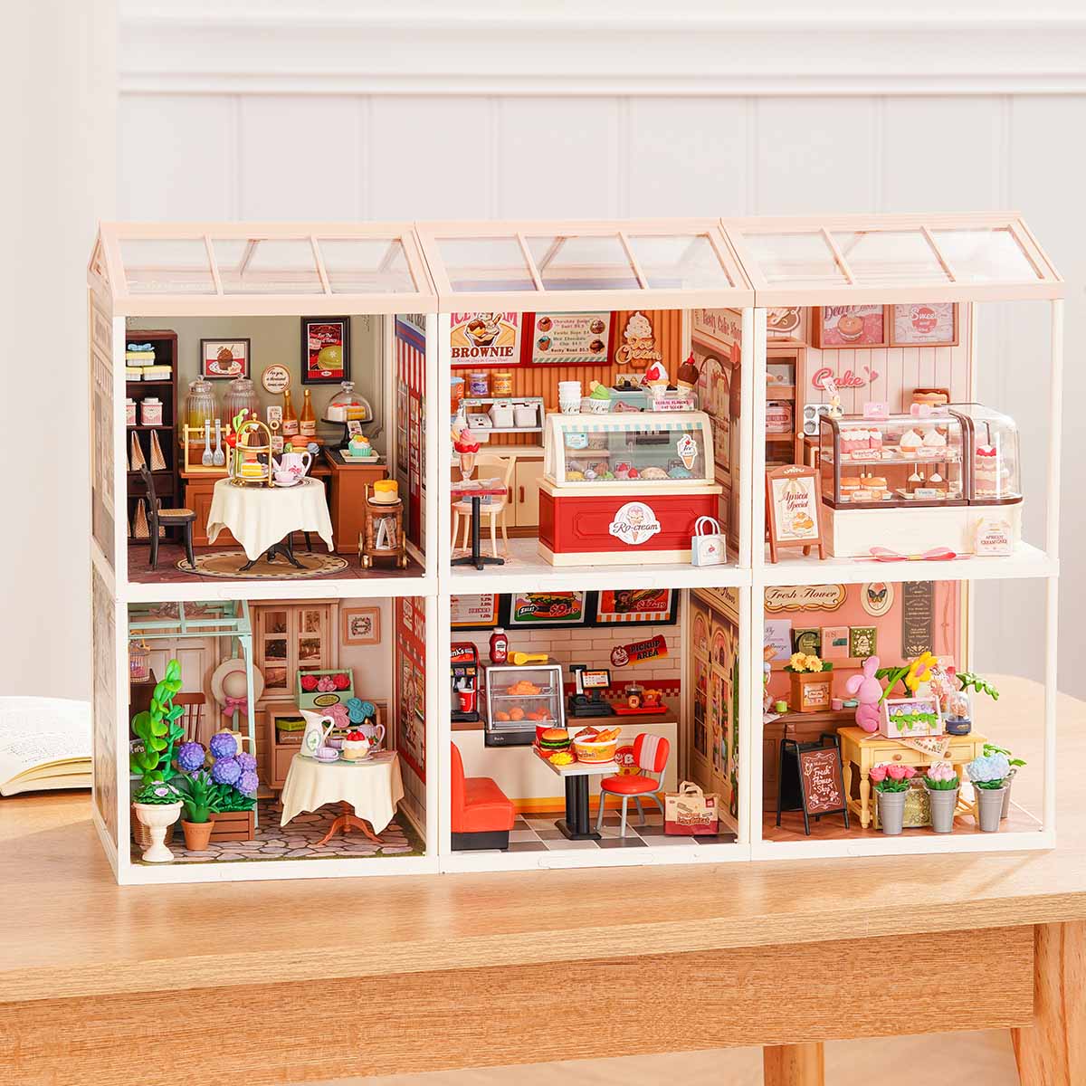 Rolife Super Creator Series 6-in-1 Six Grid wide miniature showing burger diner, afternoon tea, bar, ice cream, bakery, and flower shop rooms in a front-facing panoramic arrangement on a desk.