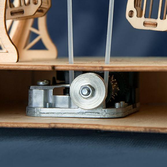 Rolife Ferris Wheel TGN01 base mechanism close-up showing silver clockwork motor and drive gear on wooden shelf