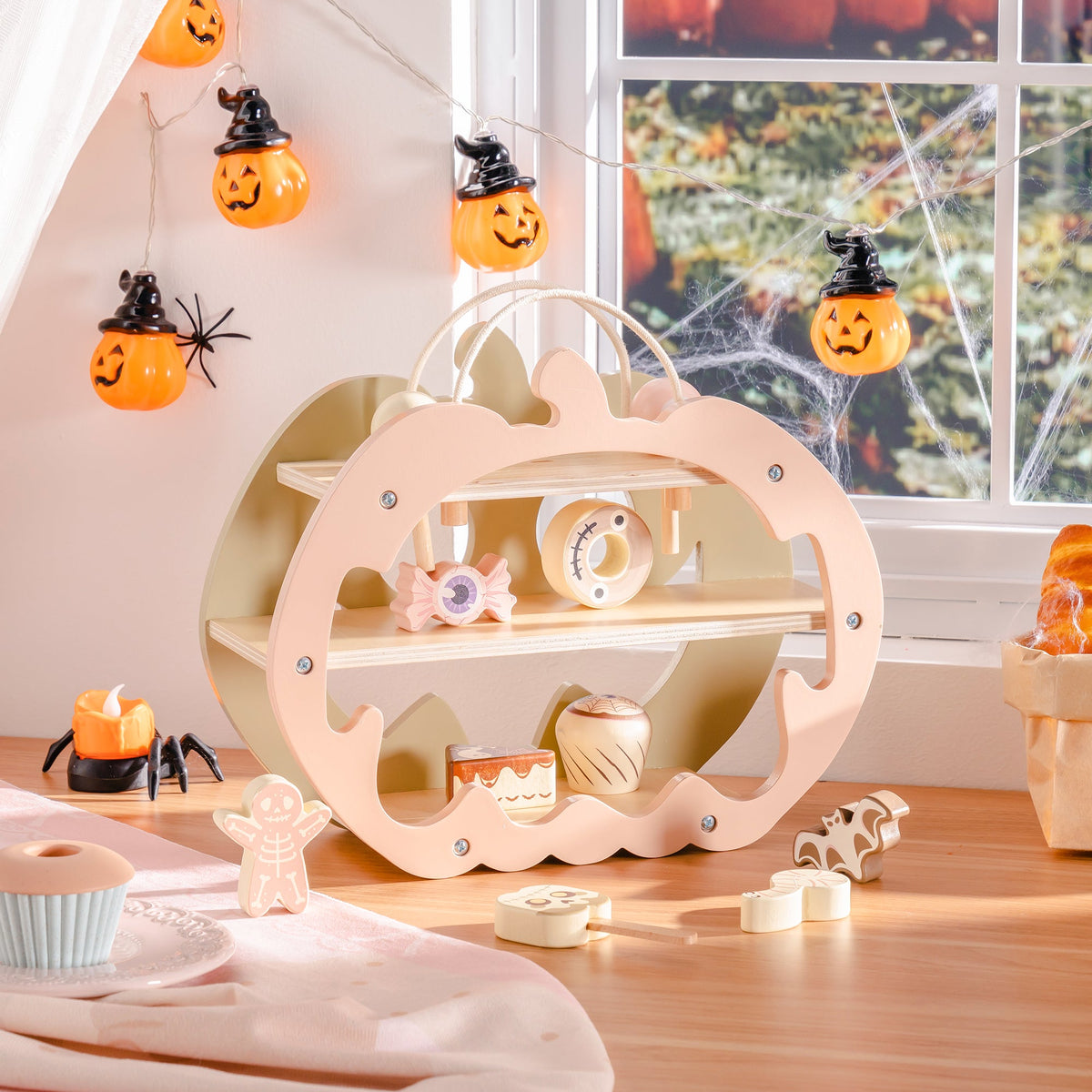 ROBUD Halloween Candy House pumpkin playset front view showing jack-o-lantern face cutouts and cream-painted wood on spider-decorated windowsill