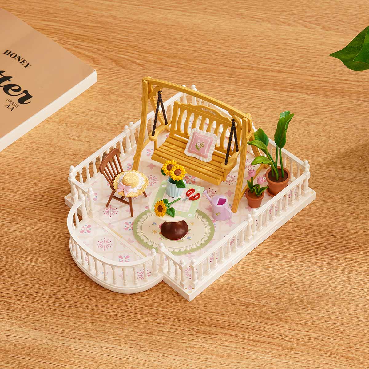 Rolife Super Creator Extension Pack terrace DIY miniature set with a sunny porch, swing bench, sunflowers, potted plants, and white fence on a wooden desk