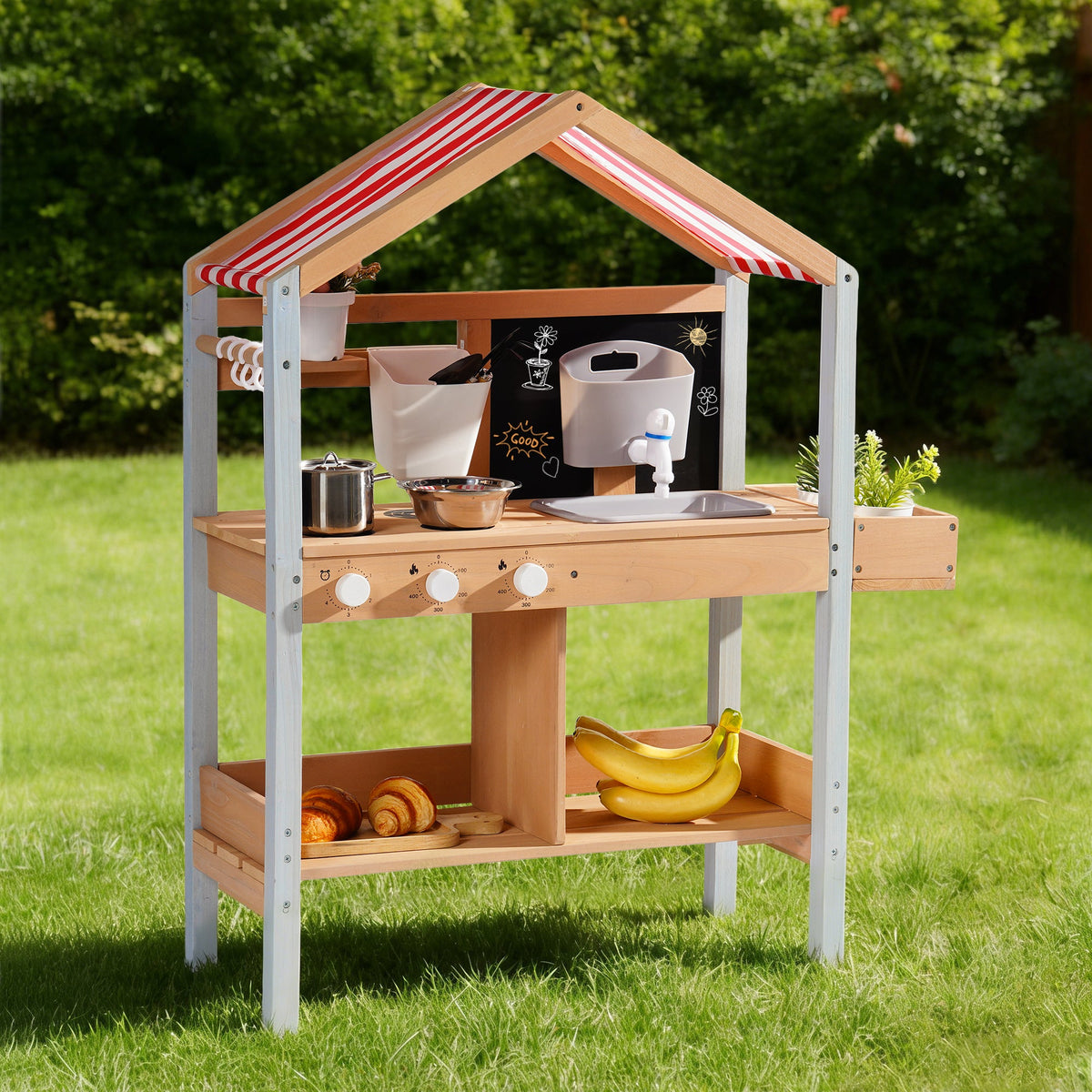 ROBUD outdoor mud kitchen with canopy standing alone on green lawn showing full structure with stainless knobs and two storage shelves
