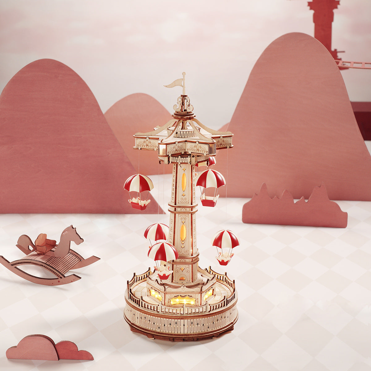 ROKR Parachute Tower music box in natural wood with glowing base lights among pink hills and a miniature rocking horse