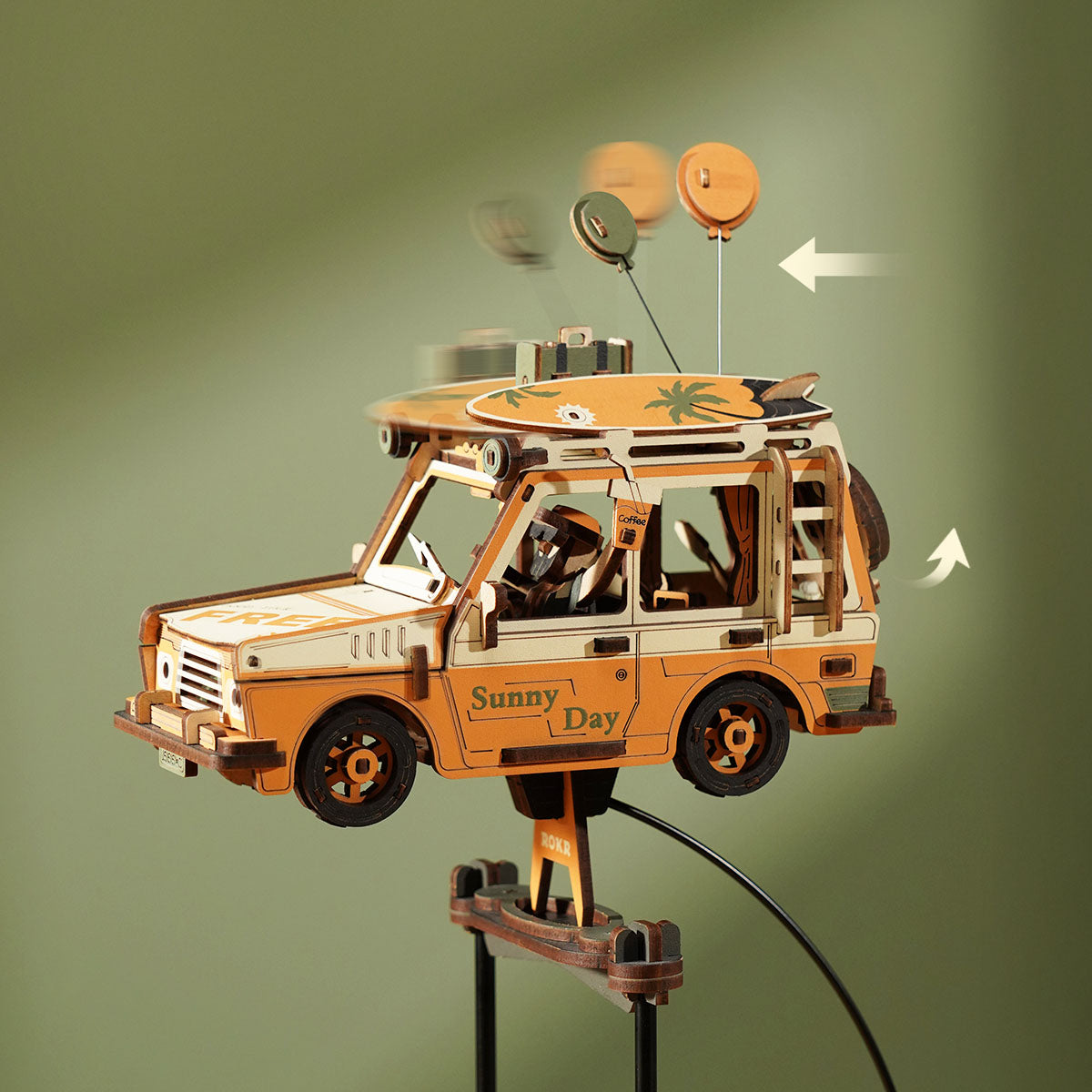 ROKR Road Tripper Gravity Swing MCD03 orange wooden SUV with two balloons and surfboard swinging freely on its pendulum stand against sage-green background