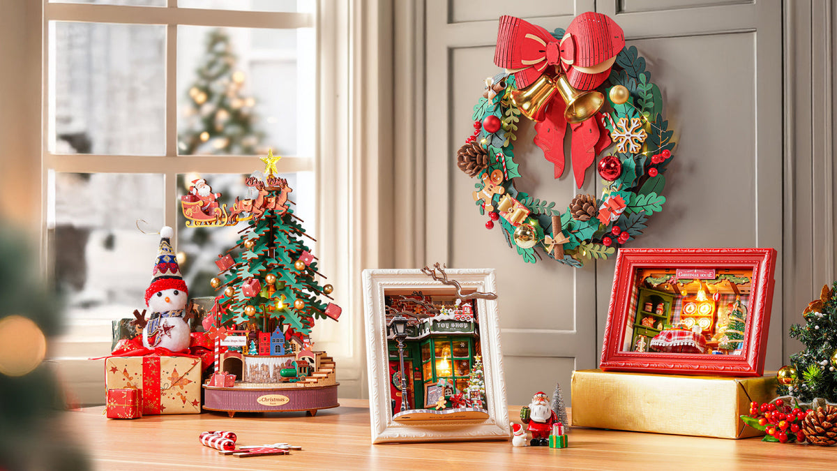Rolife Christmas Wreath TGL04 on a shelf beside a rotating Christmas tree and illuminated book nook with fireplace