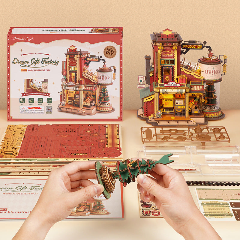 ROKR Dream Gift Factory EAB01 wooden music box and retail box flat lay showing parts sheets and hand placing green piece