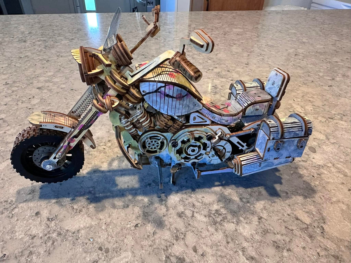 Fan-assembled ROKR Cruiser Motorcycle 3D wooden puzzle placed on a granite countertop showing detailed wood and metal finish with chrome accents