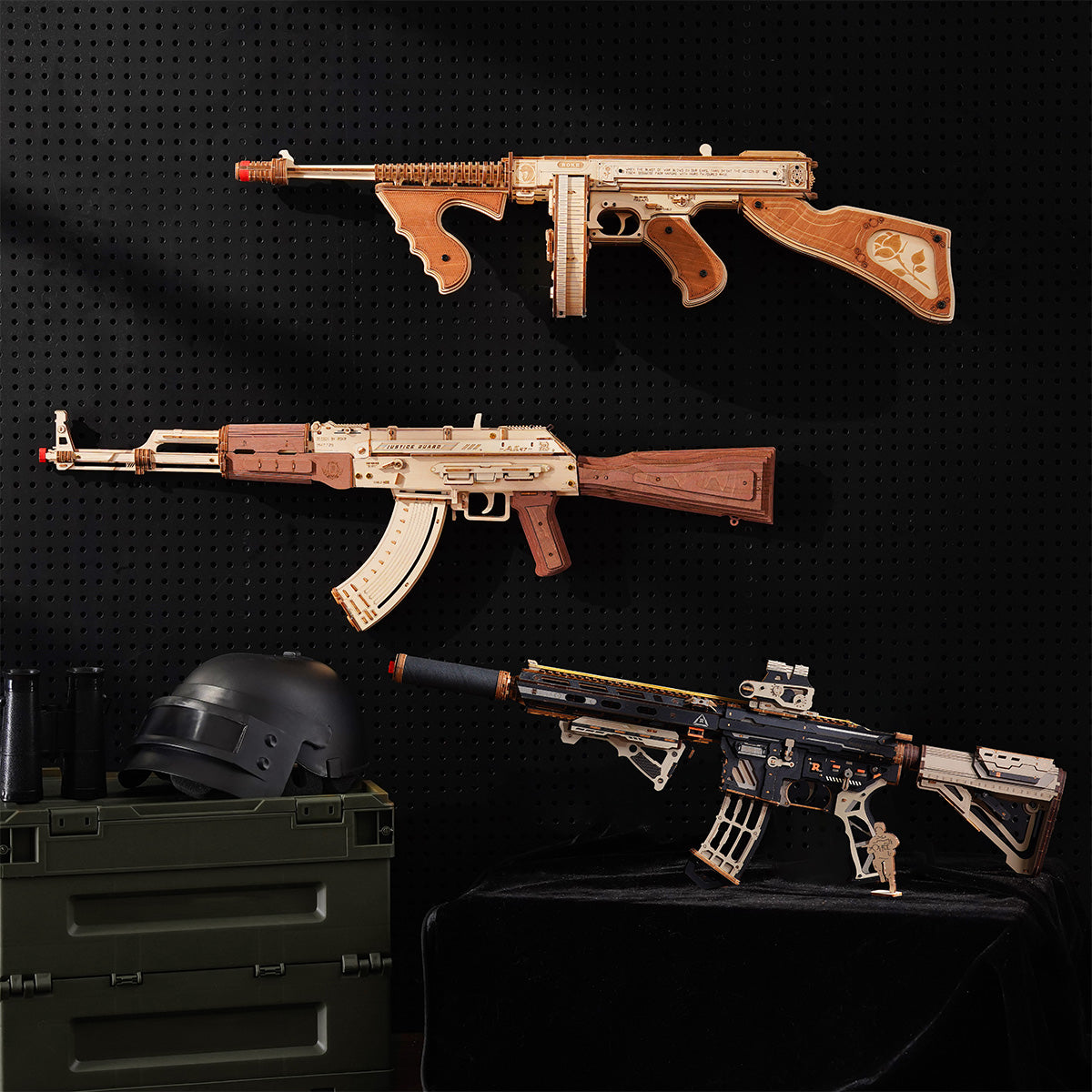 Three wooden puzzle firearm models mounted on a pegboard above a military helmet, ranging from submachine gun to rifle.