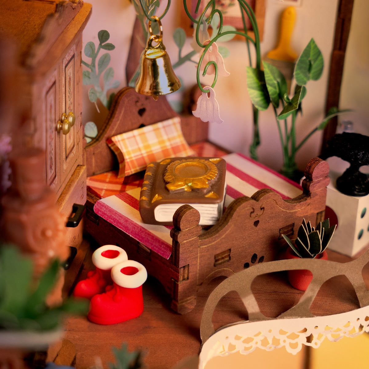 Hands assembling the Rolife Fairytale Tree House DG179 miniature fitting a decorative wooden drawer unit with miniature accessories and instruction guide on a light green surface