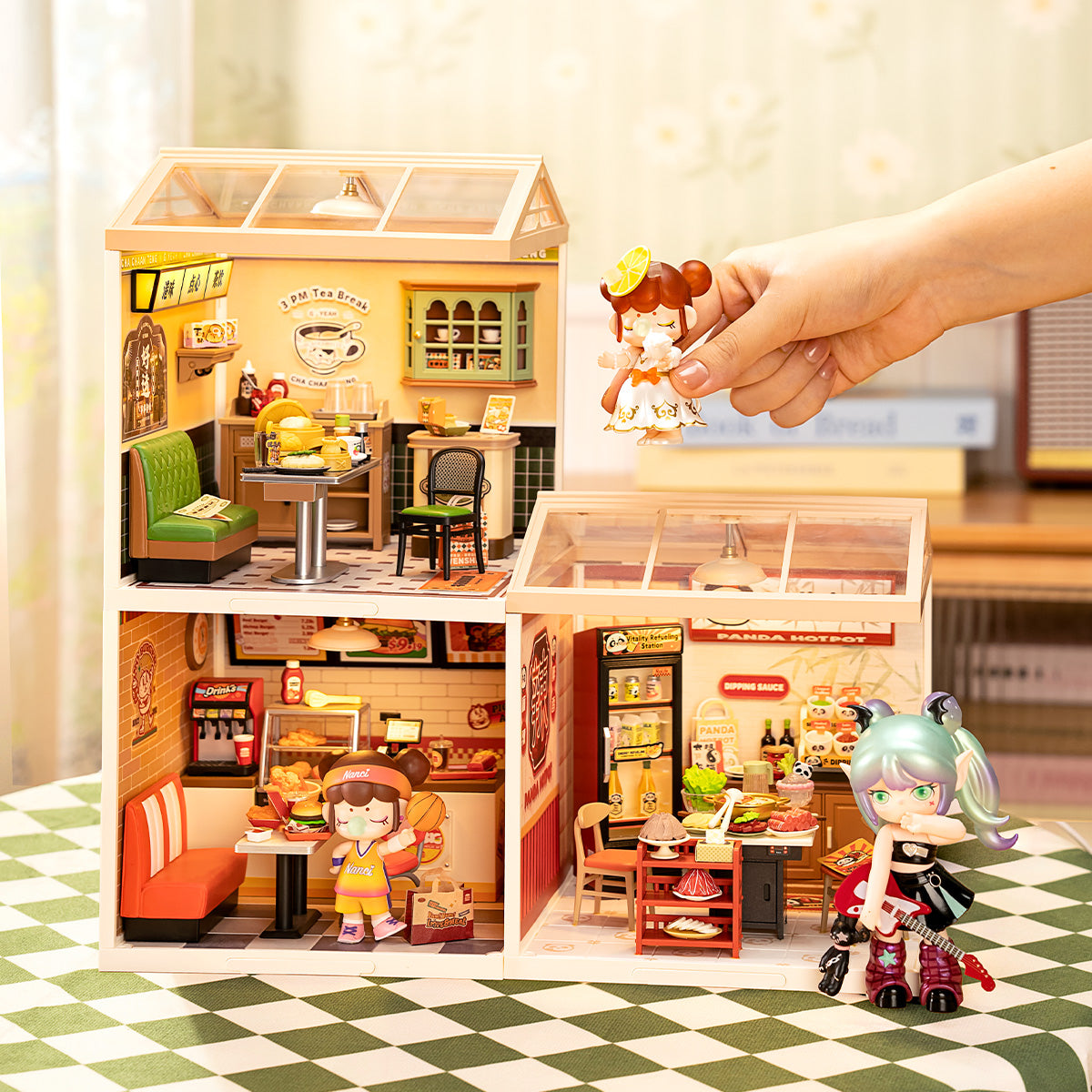 Rolife Hong Kong Bites Cafe DW021 and two other Super Creator rooms displayed in a three-story stack with a hand placing the lemon Suri doll onto the top floor cafe scene