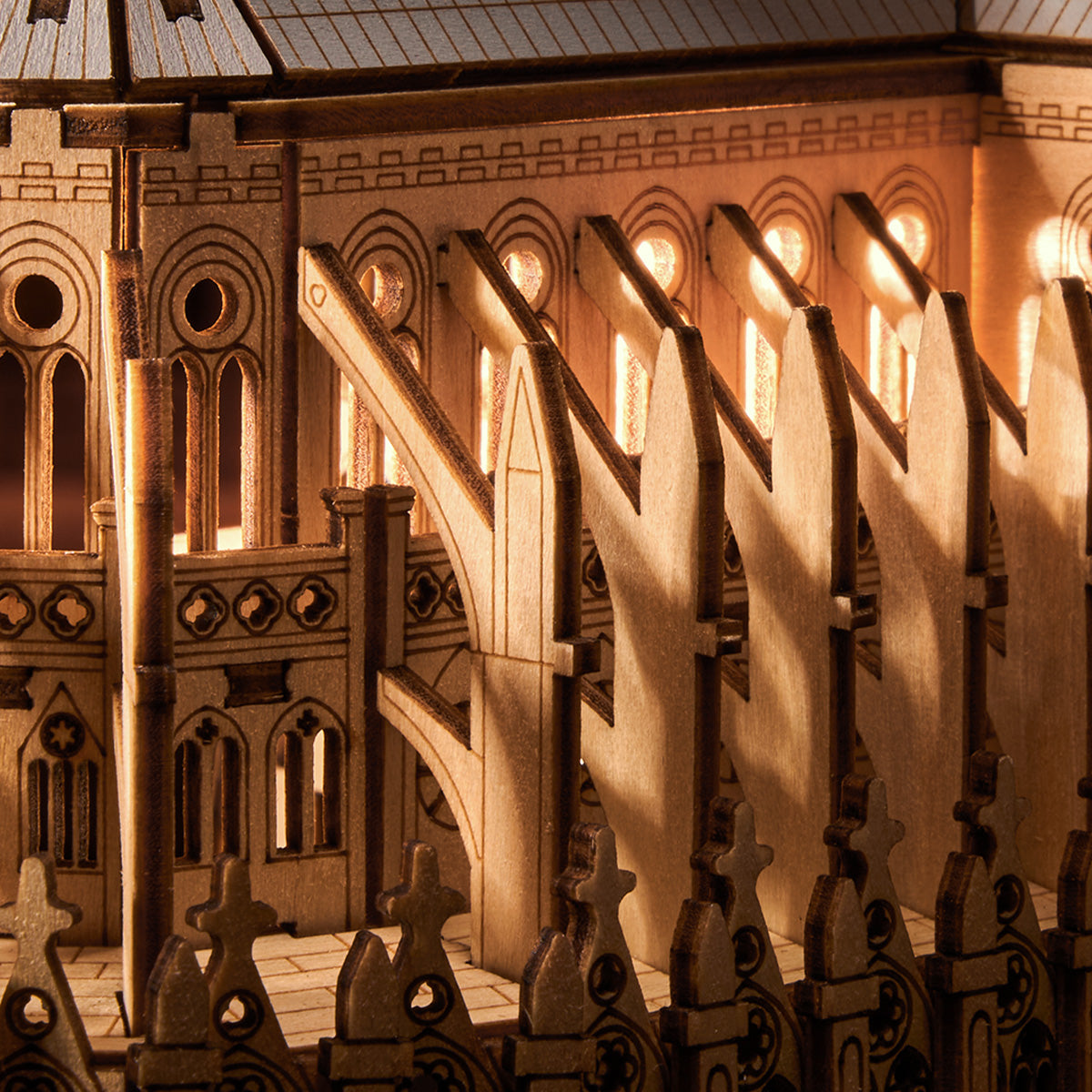Rowood Paris Cathedral TG511 wooden puzzle photographed from the rear-side showing the apse, flying buttresses, and central spire on a wooden surface with soft background lighting