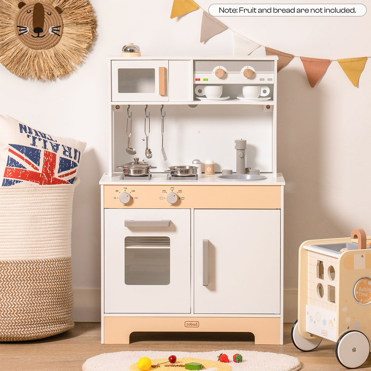 ROBUD white and natural wood play kitchen in room setting with toy cart and boho woven decor.