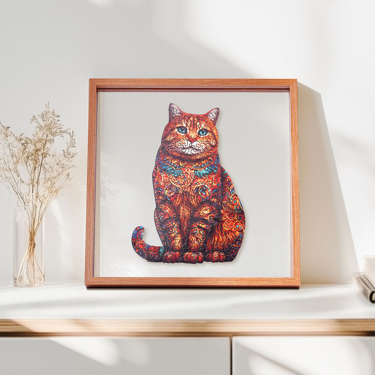 Rowood Exotic Cat orange tabby wooden jigsaw puzzle in a shadow box frame resting on a shelf beside a glass vase with dried stems