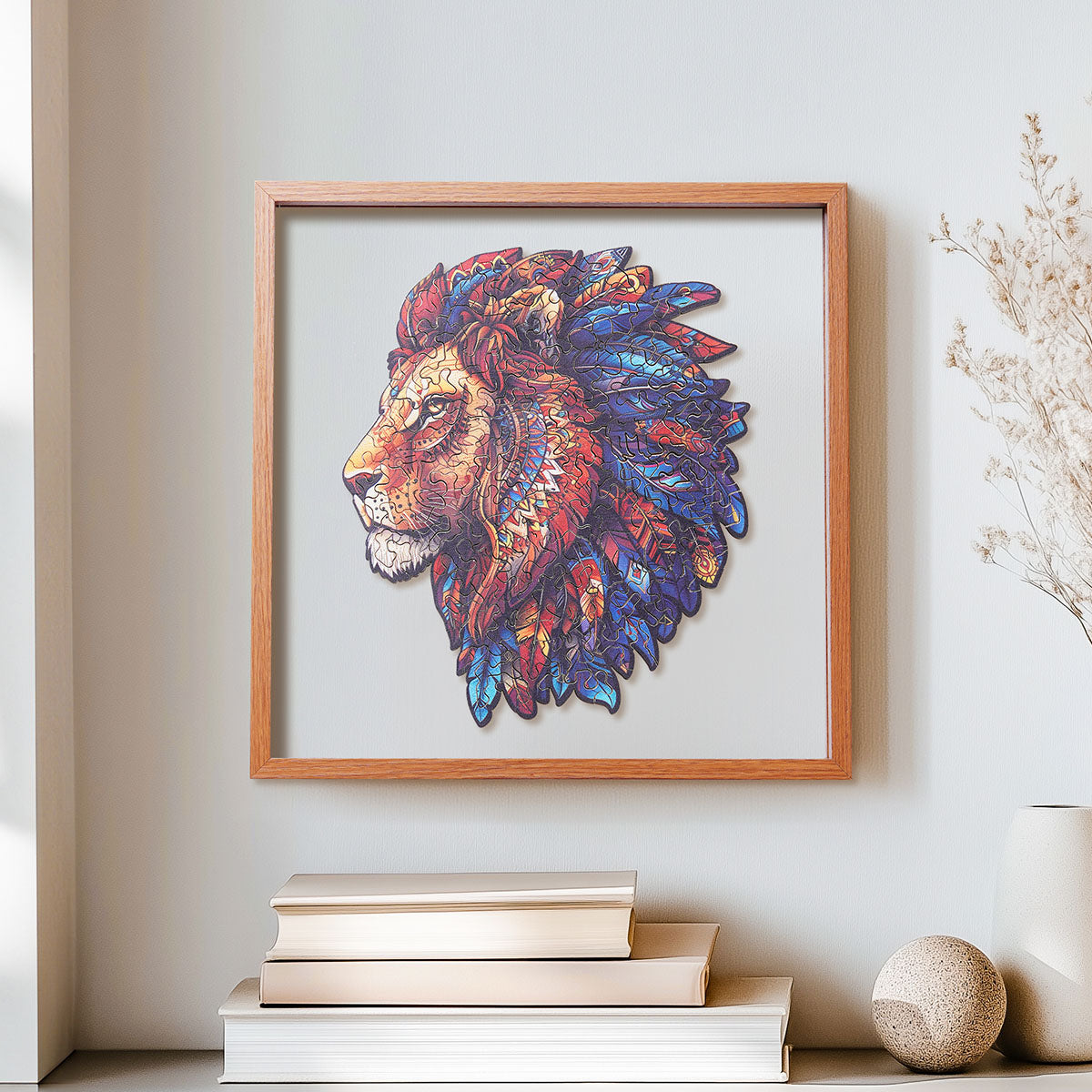 Rowood Lion King wooden jigsaw puzzle in a shadow box frame hanging on a wall above a stack of books and a stone sphere decoration