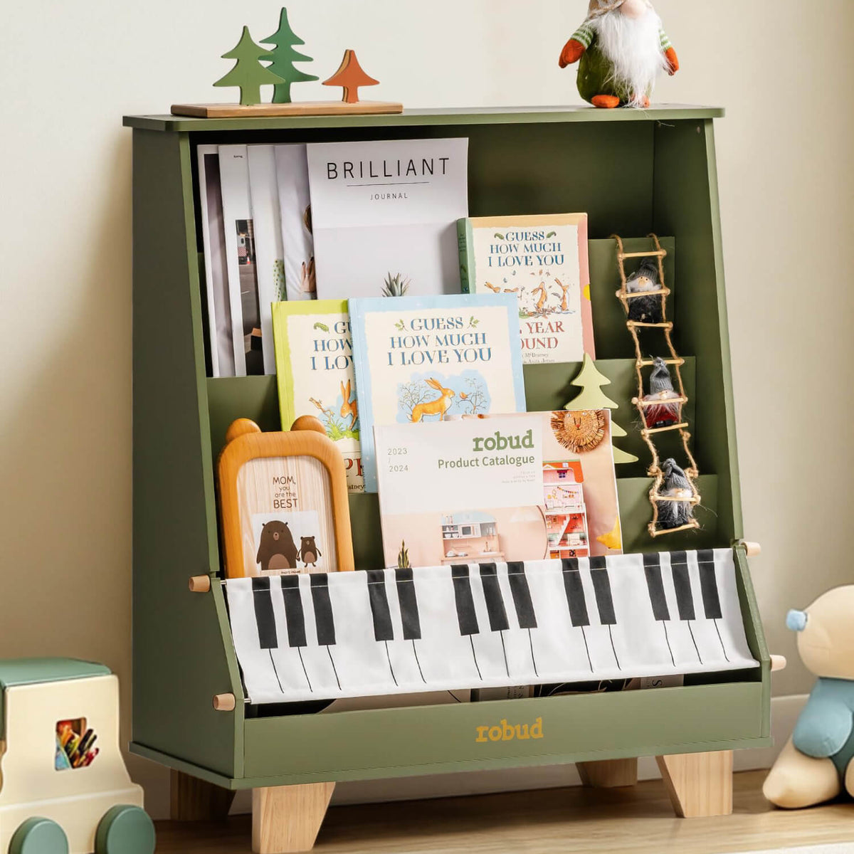 ROBUD green wooden kids bookshelf with piano keys panel at the base, holding colorful children's books and small decorative trees on top