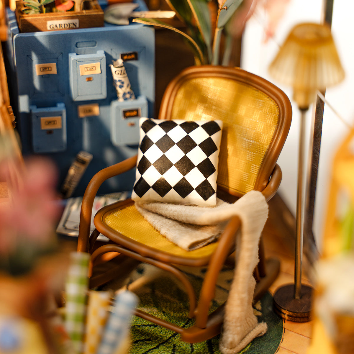 Rolife miniature scene close up showing wooden chair with black and white checkered pillow and yellow cushion