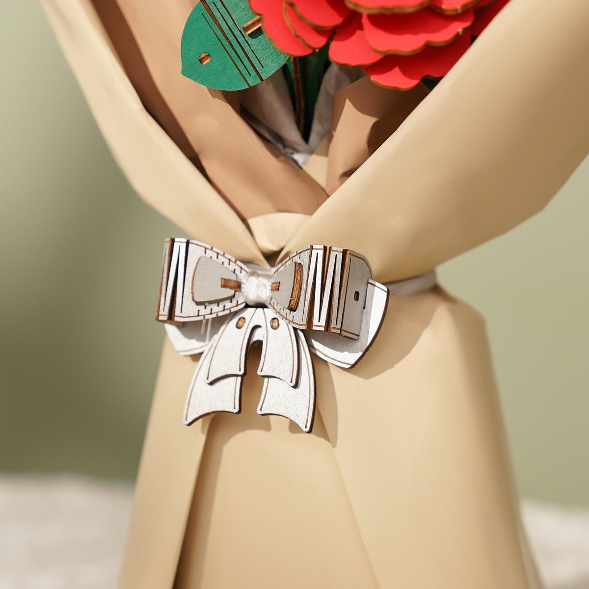 Detailaufnahme des Rowood Blumenstraußes mit cremefarbener Umhüllung, Schleife und gestaffelten Holzblumenstielen.