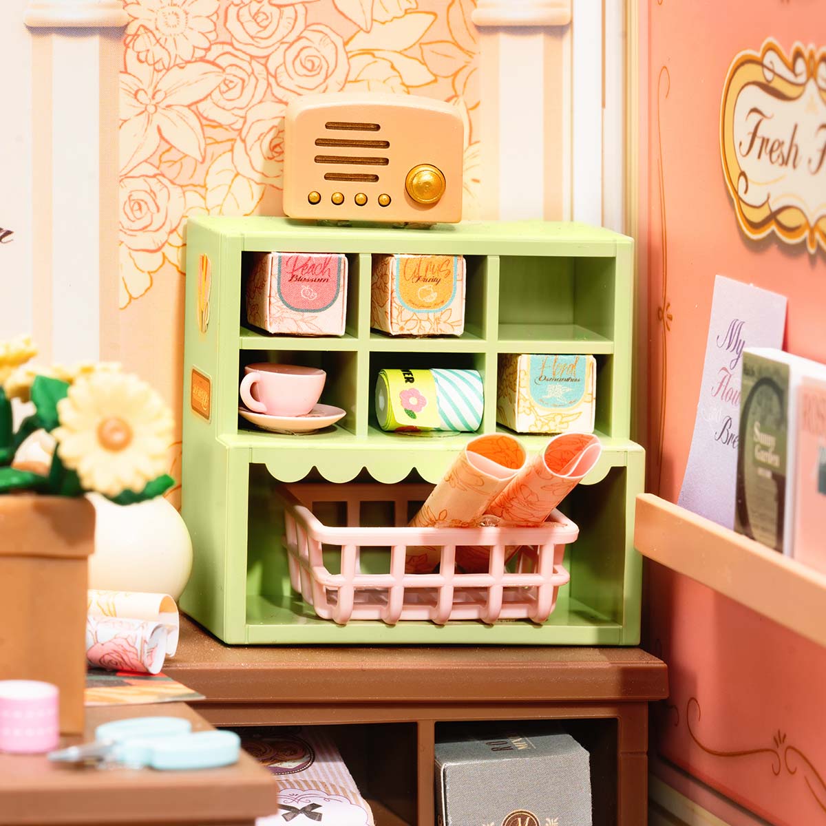 Rolife Fresh Flower Shop DIY miniature house DW017B top-down view revealing the fully decorated flower boutique interior with potted blooms, green cabinets, vintage radio, and a chalkboard welcome sign.