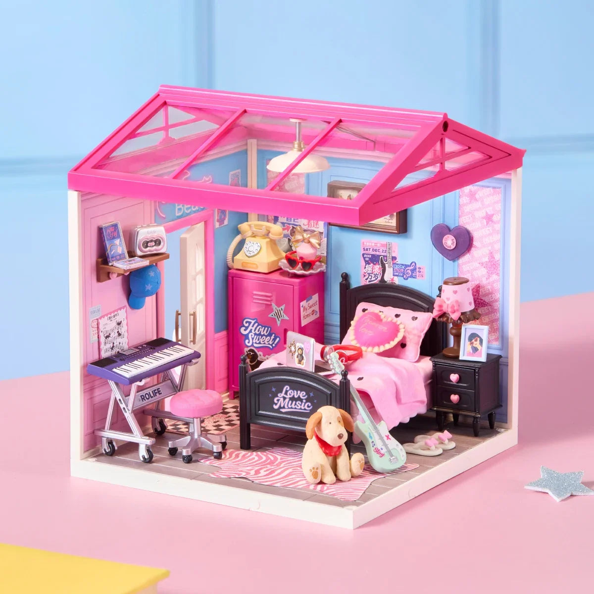 Rolife-Miniatur-Schlafzimmer auf einer rosa Fläche mit rosa Dachrahmen, blauen Wänden, schwarzem Bett, rosa Bettwäsche, Keyboard, Gitarre, Hundefigur und Musikpostern.