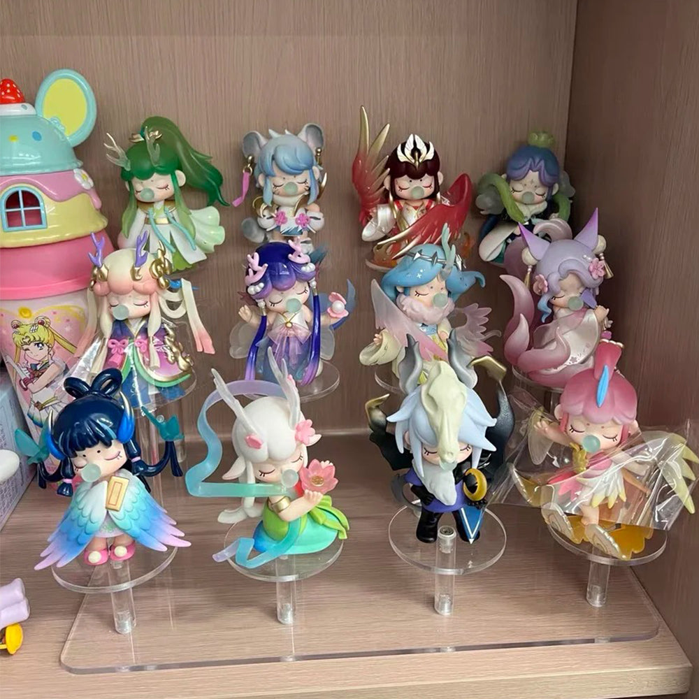 Rolife Nanci Sweet Time blind box figures in four pastel colors arranged on a desk beside stacked pink gift boxes and a keyboard.