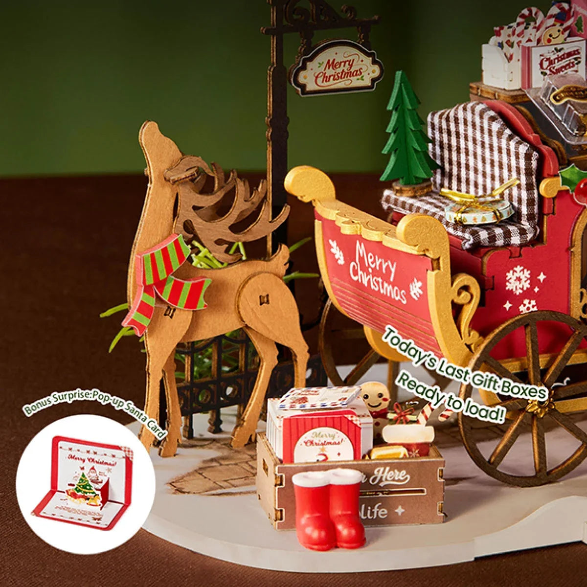 Nahaufnahme eines Holzrentiers mit rot-grünem Schal neben rotem Schlitten, Geschenkkiste, roten Stiefeln und einer eingeblendeten Weihnachtsmann-Pop-up-Karte.