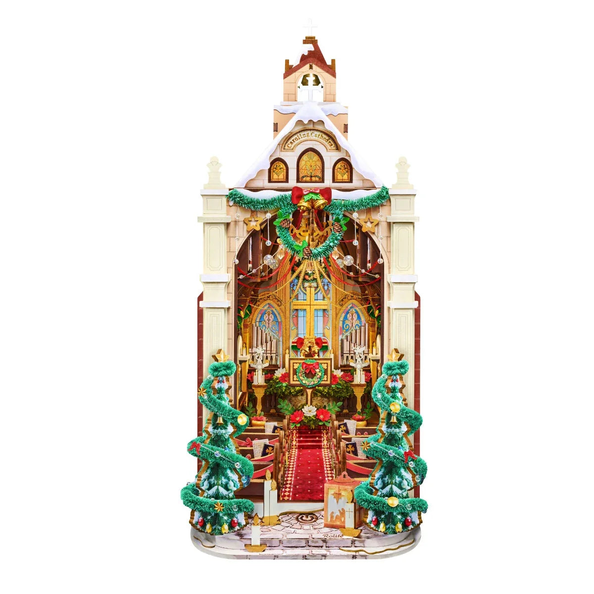 Rolife-Weihnachtskathedrale im Miniaturformat mit leicht verschneitem Dach, Bogeneingang, Kranz, zwei geschmückten Bäumen und beleuchtetem Innenraum.